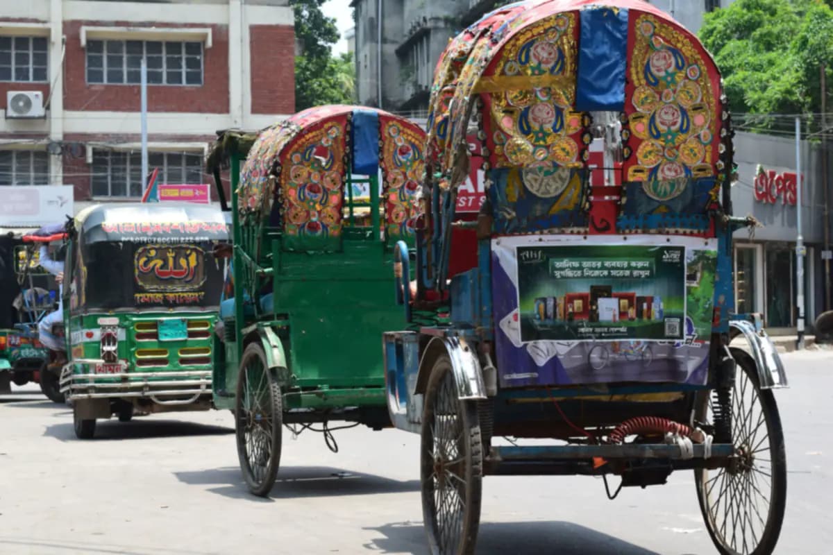 Two cycle rickshaws with hoods painted in red, gold and blue flowers, next to a green auto rickshaw on a Dhaka street