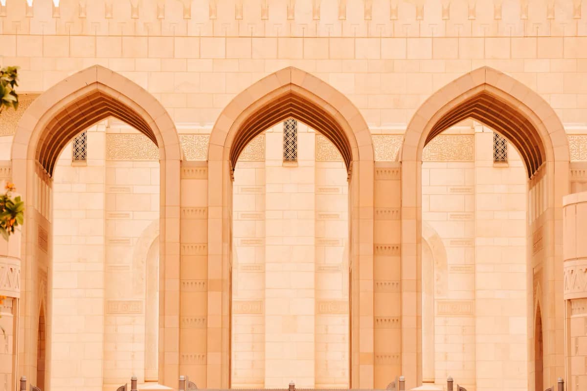Three pointed stone arches with carved calligraphy panels on the Sultan Qaboos Grand Mosque