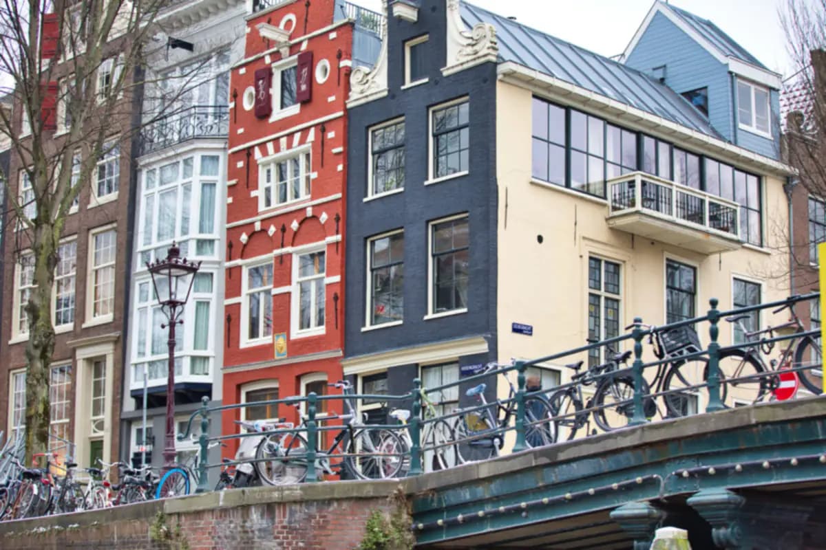 Bicycles parked along a canal bridge below tall narrow houses at the corner of the Herengracht and the Leliegracht