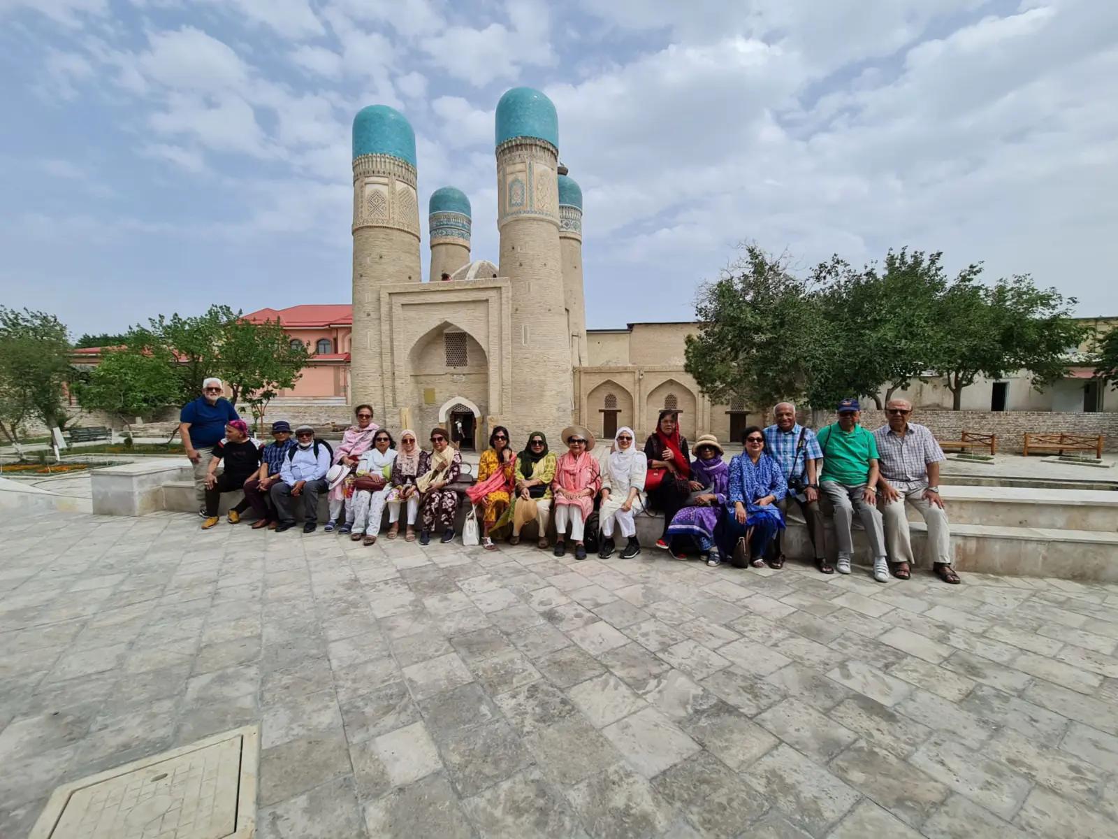 An NCL tour group seated in front of Chor Minor in Bukhara, Uzbekistan